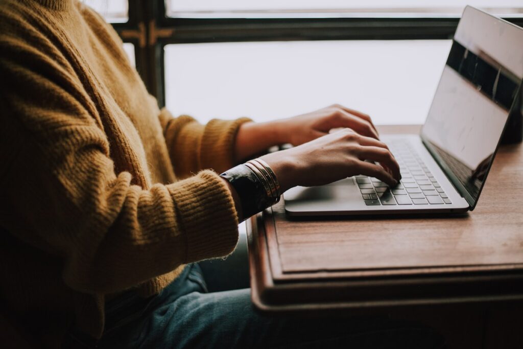 Student writing and typing on a laptop